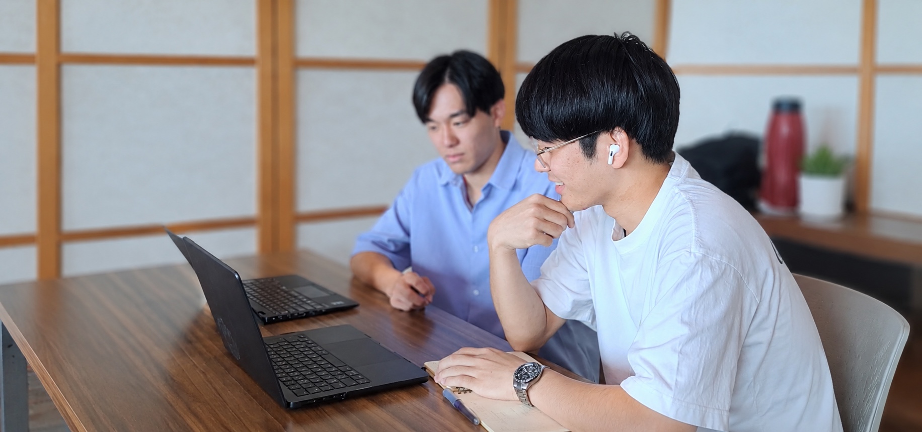 合宿の作業部屋で、2人が画面を見ながら話しているところ